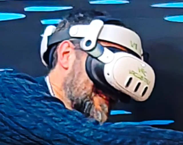 Uomo con barba che indossa un visore per la realtà virtuale, ripreso di profilo.